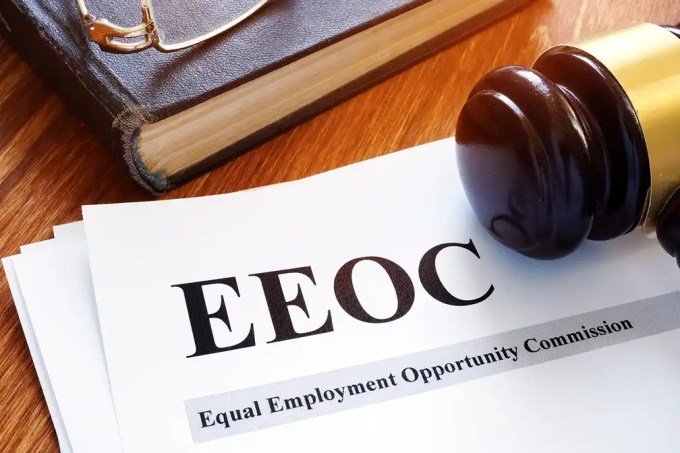 Gavel resting on EEOC paperwork labeled Equal Employment Opportunity Commission on a wooden desk.