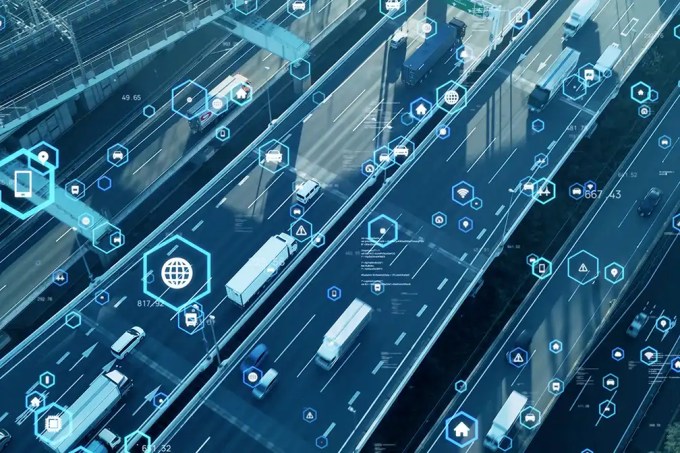 Highway with moving traffic overlaid by blue digital icons and hexagons symbolizing connected smart transport networks. (Informative)