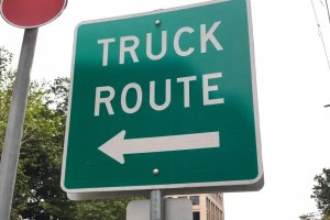Truck route sign with a left-arrow indicating direction leftwards.