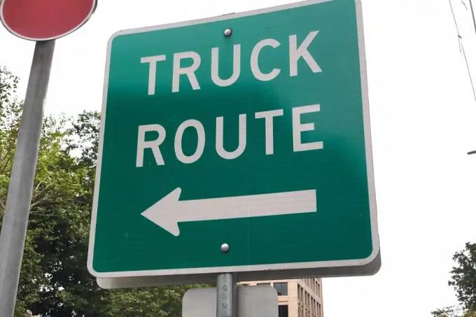 Truck route sign with a left-arrow indicating direction leftwards.